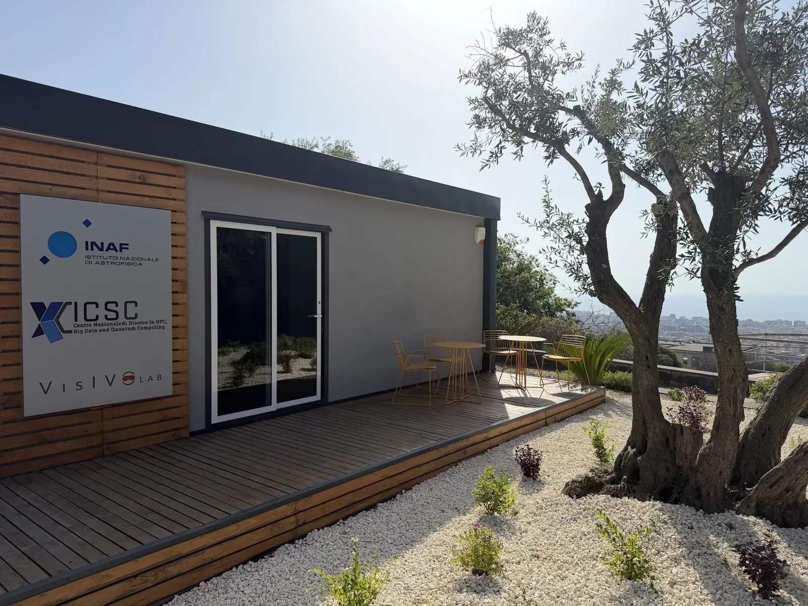 The VisIVO LAB pavilion, its wooden deck and the city and sea on the horizon.